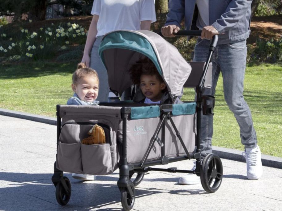 two kids sitting in delta children jeep wagon 