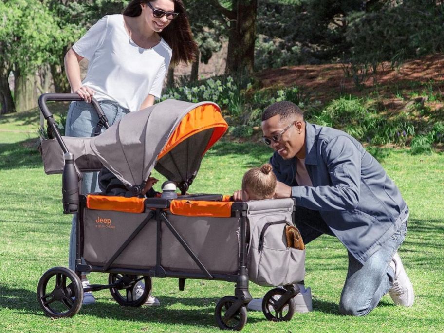 couple outside with Delta Children Store Jeep Wrangler Sport All-Terrain Stroller Wagon