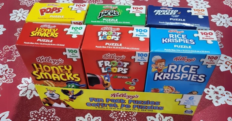 a box of 6 puzzles that look like Kellogg's Cereal Boxes on a table with a red snowflake tablecloth