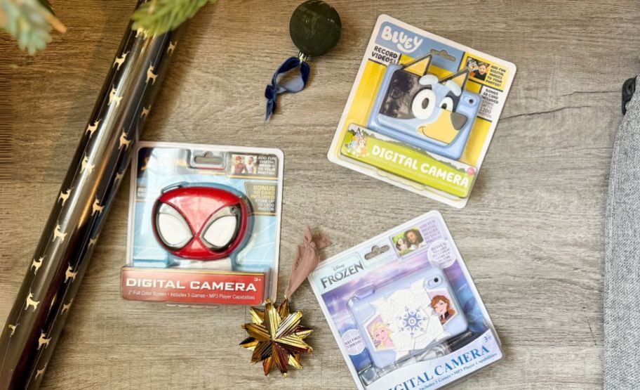 three kids character cameras shown with holiday wrapping paper 