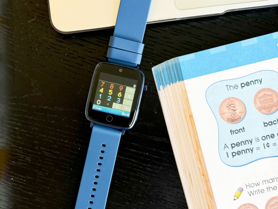 kids smartwatch displaying calculator next to math book