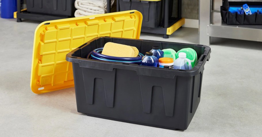 black storage tote with yellow lid in garage