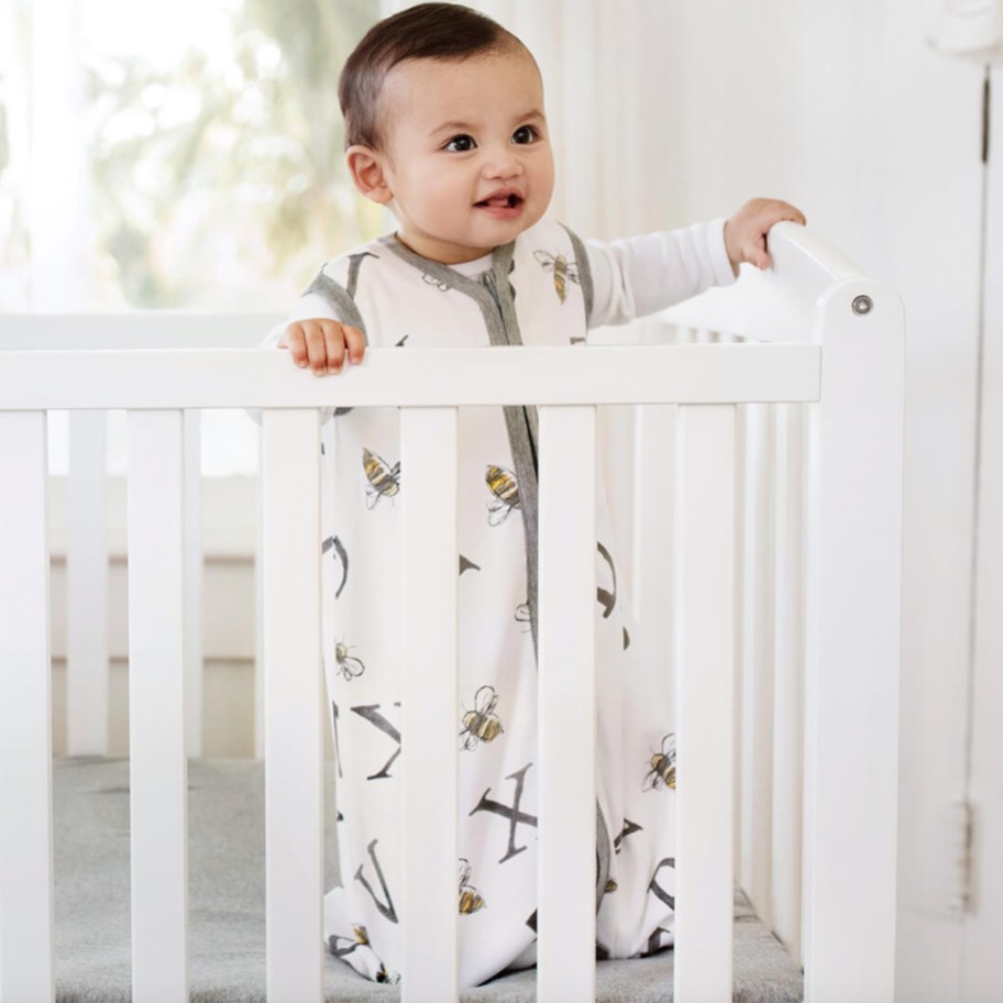 baby standing in crib in wearable blanket 