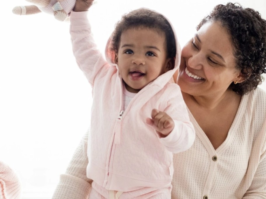 baby in pink jacket next to mom