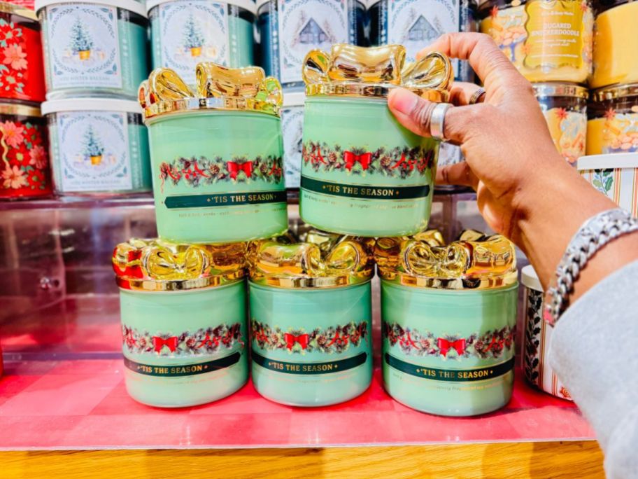 hand grabbing bath body works bow candle from display