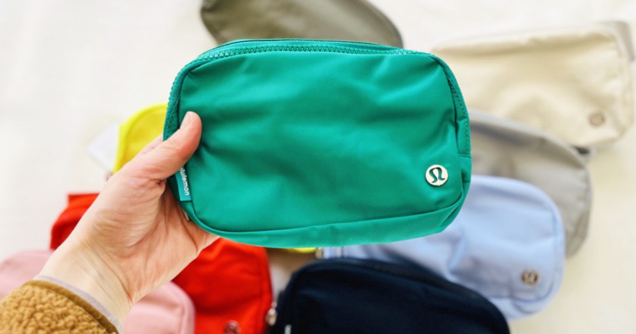 hand holding up a green lululemon Everywhere Belt Bag