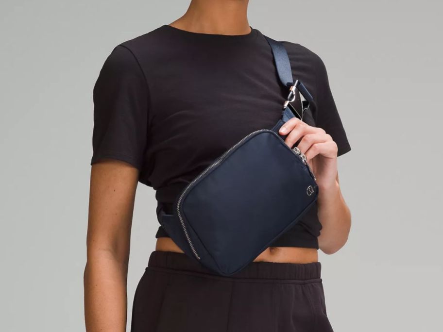 a woman wearing a navy lululemon belt bag 