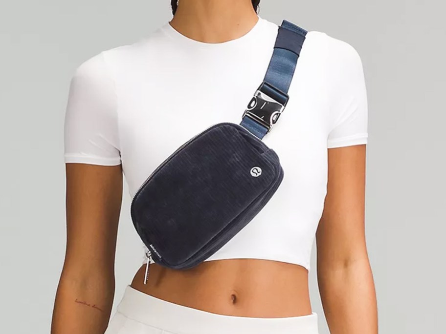 woman in white outfit with navy blue belt bag across chest