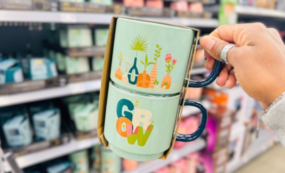 a womans hand holding a 2 pack of stacking mugs