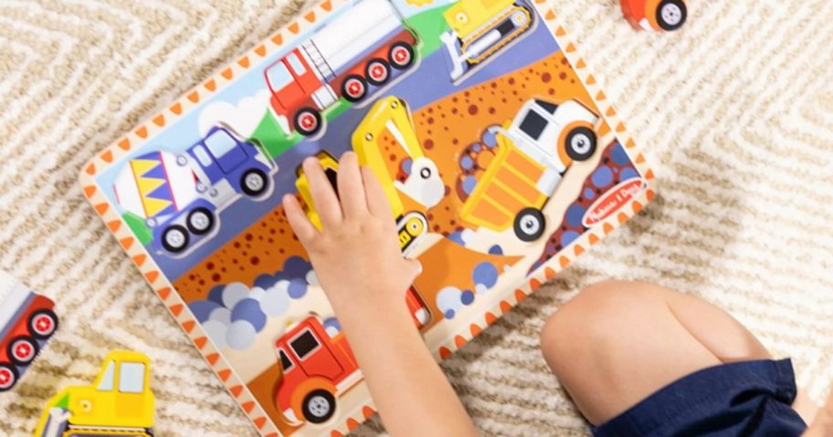 A child playing with a Melissa & Doug Construction Vehicles Puzzle 