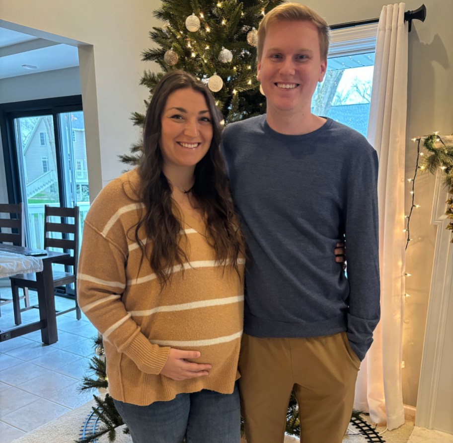 expecting couple standing in front of christmas tree