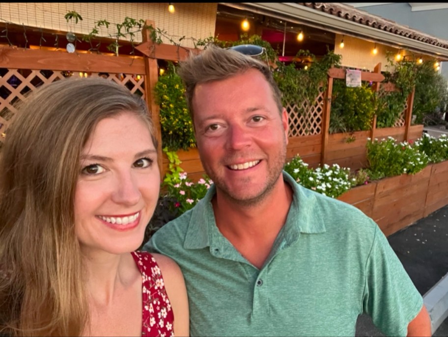 couple taking selfie smiling outside of string lit store