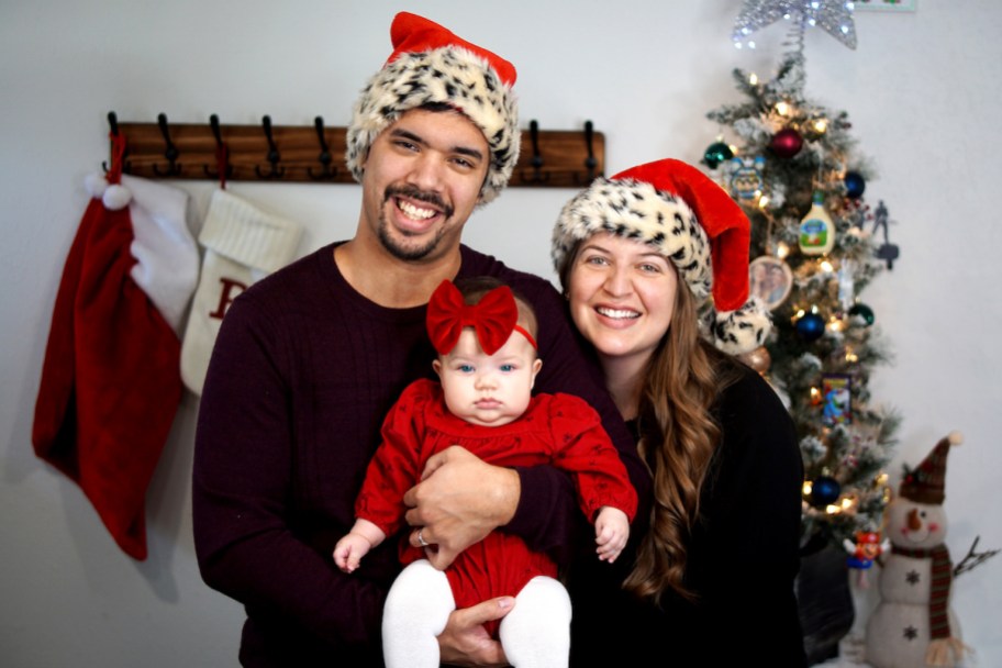 couple with christmas hats holding baby 