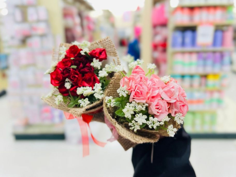 A person holding 2 small bouquets of flowers at Hobby Lobby