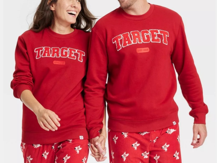 woman and man holding hands wearing matching red color sweatshirts that have "Target" spelled out in block letters - they are Target store branded sweatshirts