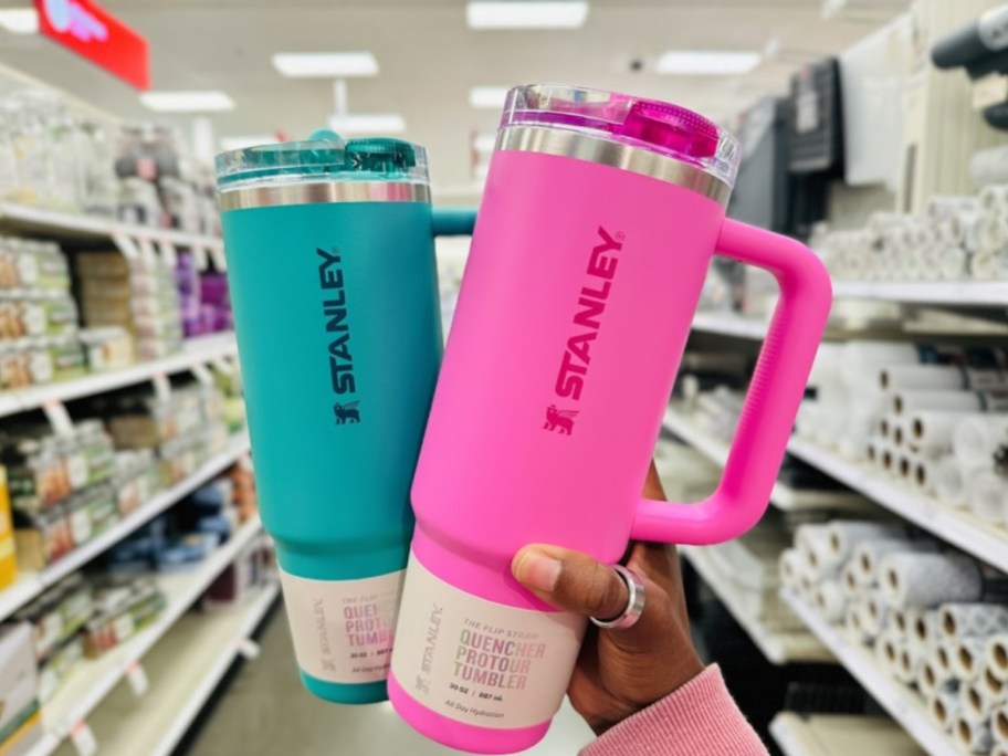 hand holding a teal color and a bright pink color Stanley 30oz tumbler