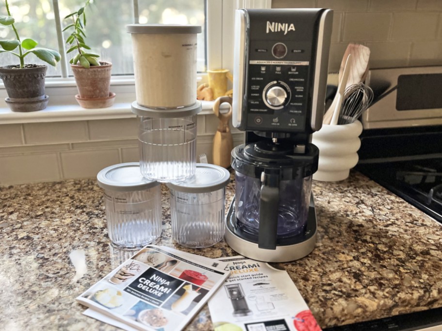 ninja creami on counter with stack of extra pints and recipe book