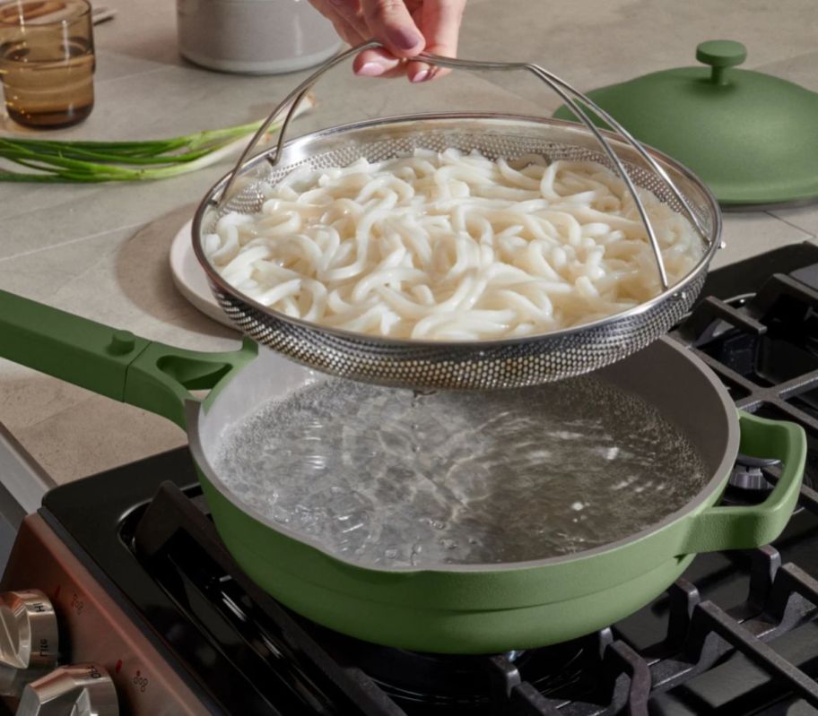 hand grabbing steamer basket out of sage always pan