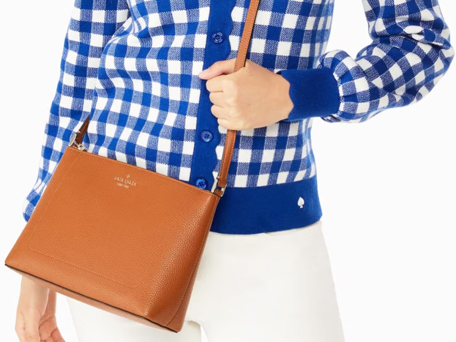 woman in a blue and white checkered sweater with a brown crossbody bag