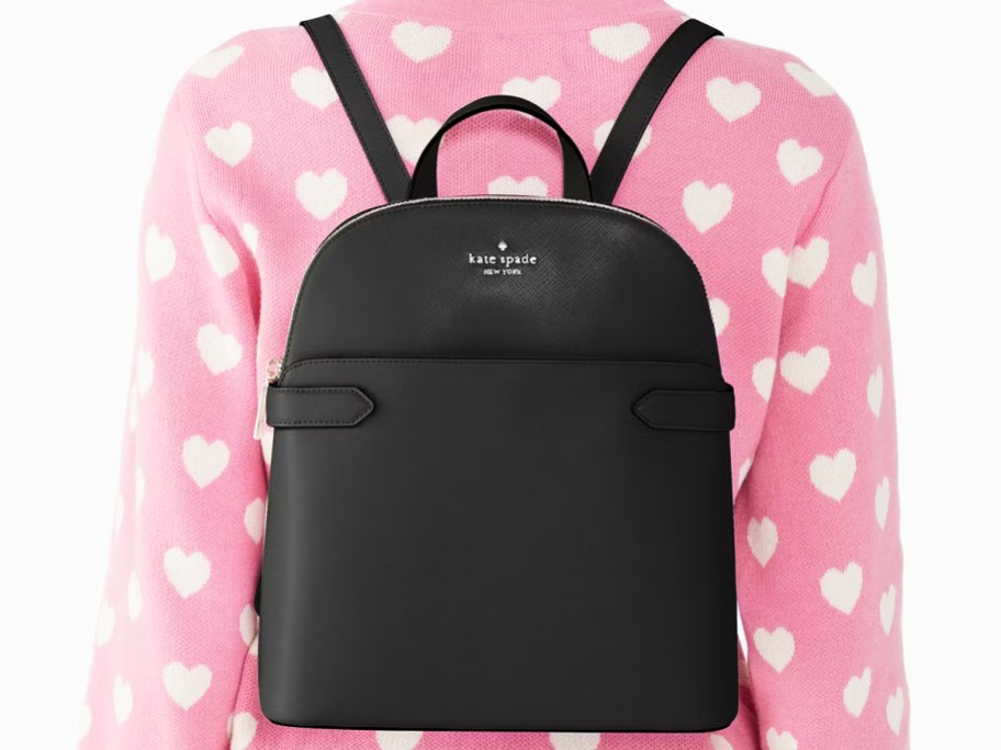 woman in a pink and white heart print sweater with black backpack