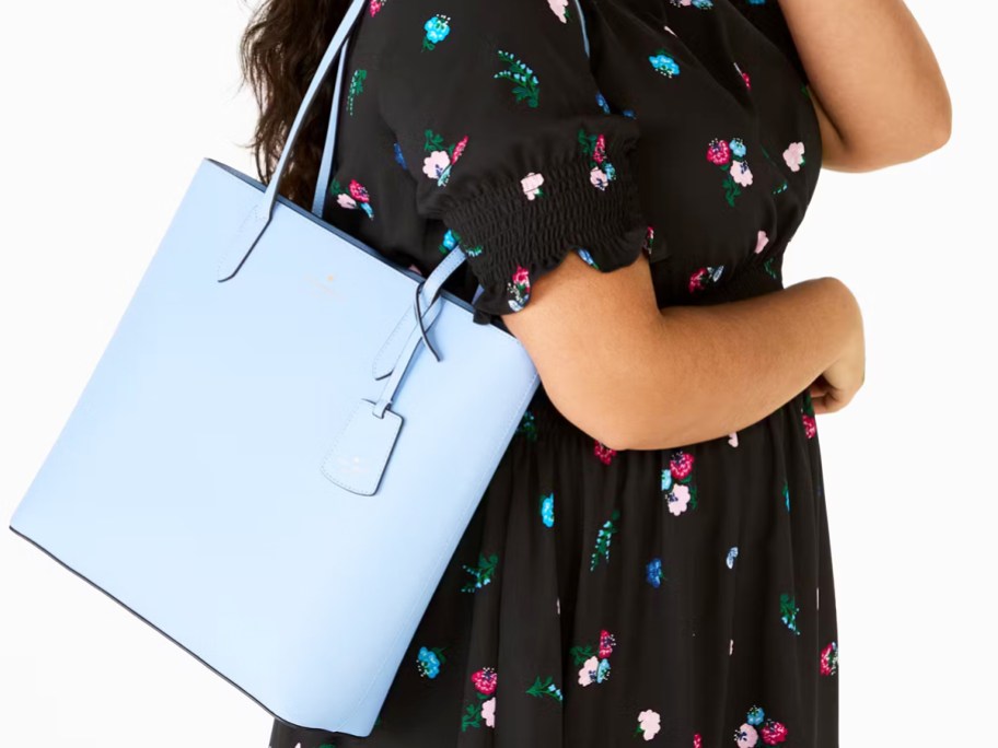 woman in a black floral print dress with a light blue tote bag