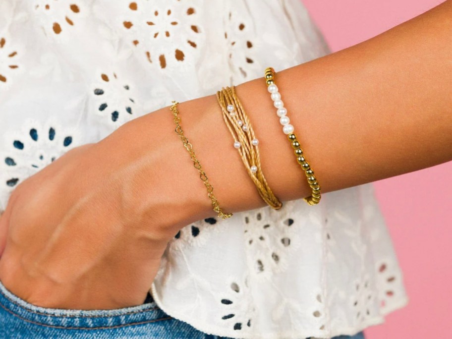 person wearing gold and pearl bracelets 