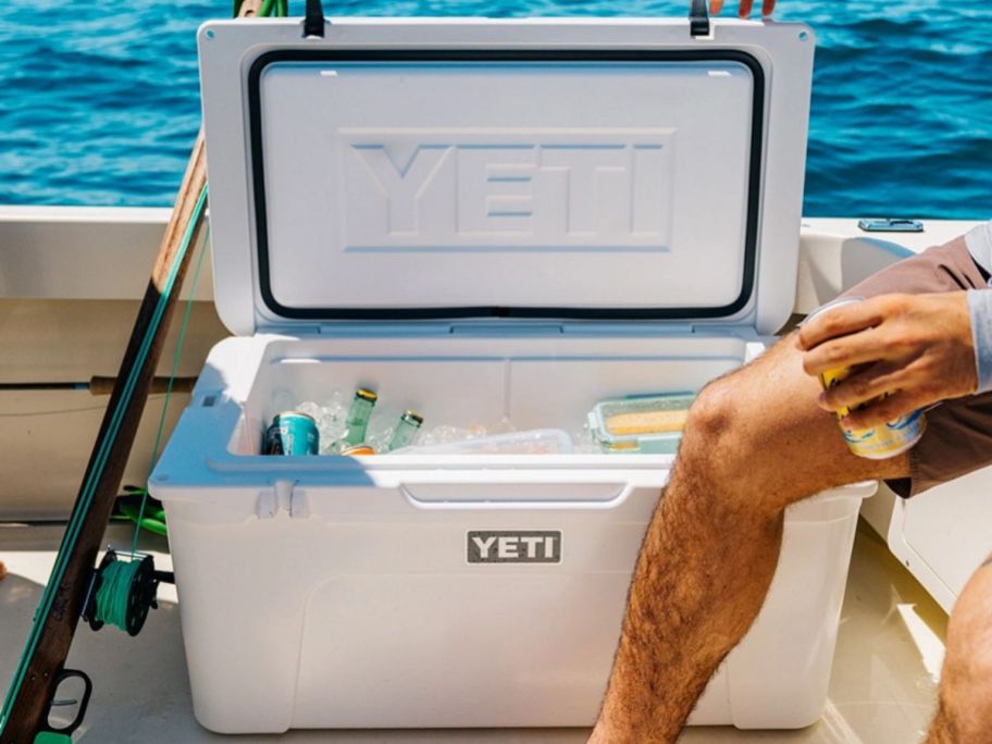 Man on a boat taking a drink from a whote YETI tundra cooler