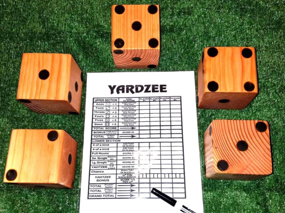 set of large wooden dice and yardzee score card on grass