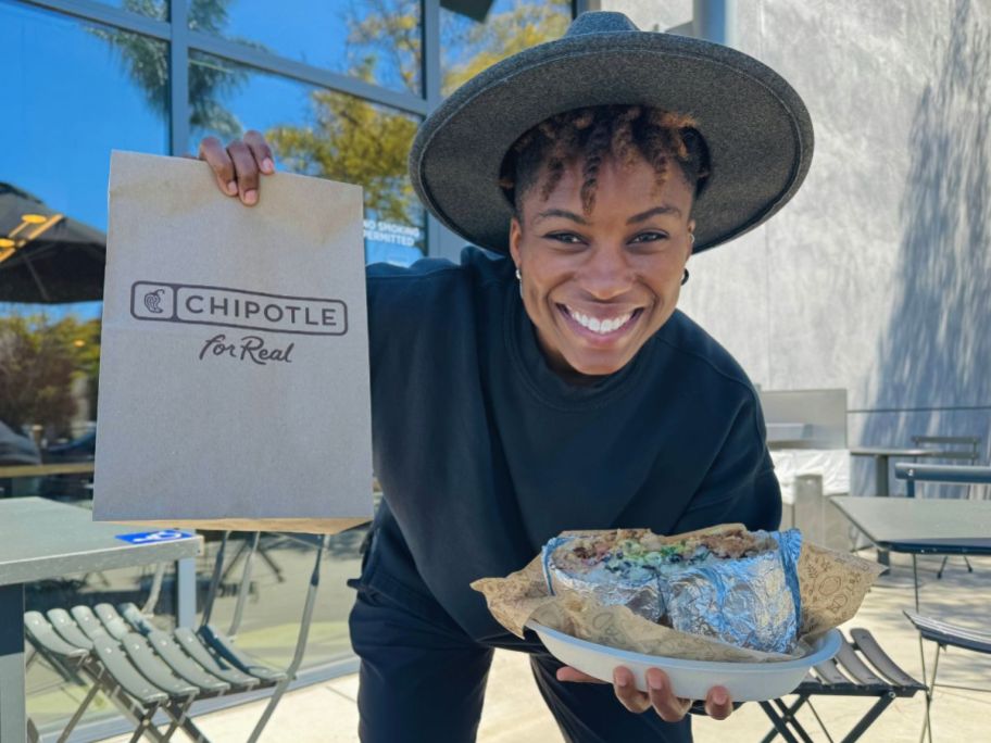 woman holding chipotle bag with entree in hands outside