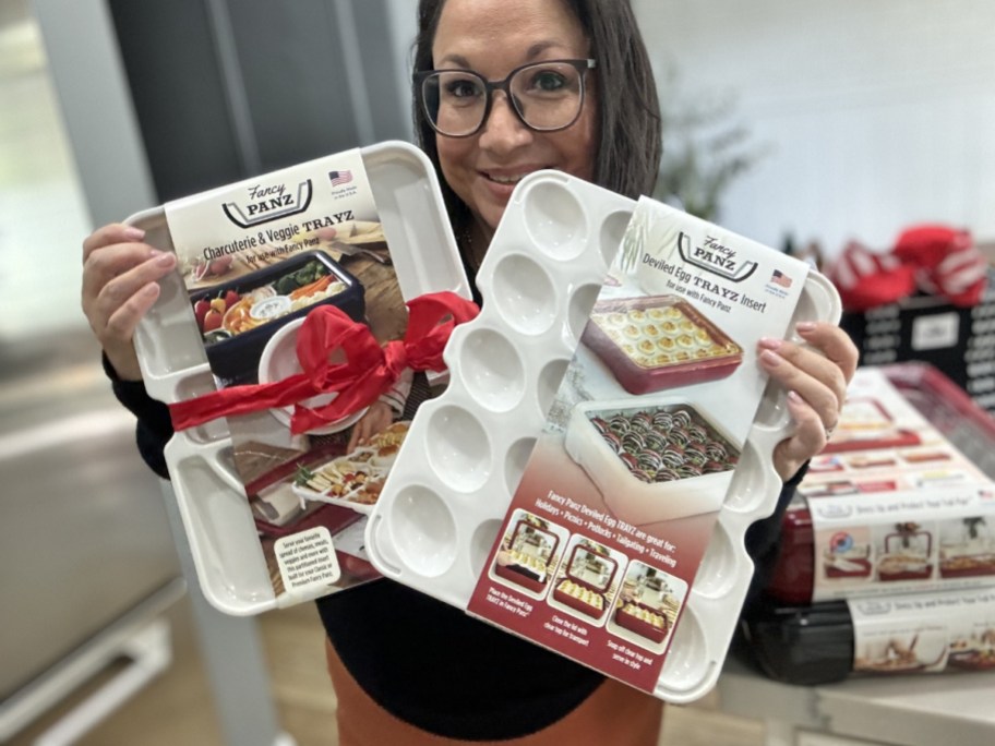 woman holding up 2 inserts for the Fancy Panz container, one is a divided insert for a charcuterie board and the other is a devilled egg tray