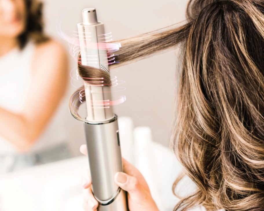 woman curling hair with air curling tool