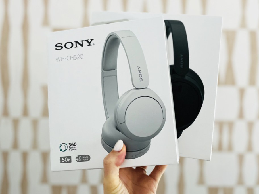 hand holding up two boxes of sony headphones