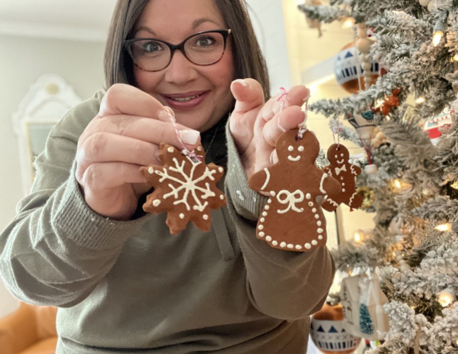 woman holding up diy christmas ornaments made with cinnamon and applesauce