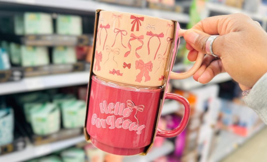 a womans hand holding a 2 pack of stacking mugs