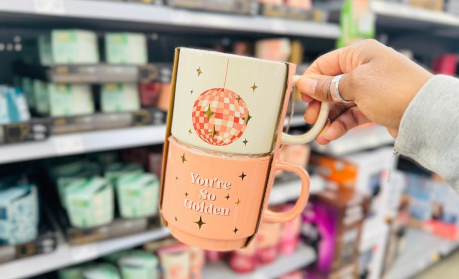 a womans hand holding a 2 pack of stacking mugs