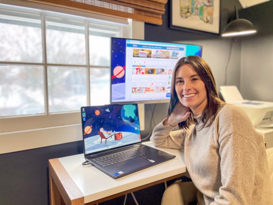 woman leaning on office desk with small and large monitors