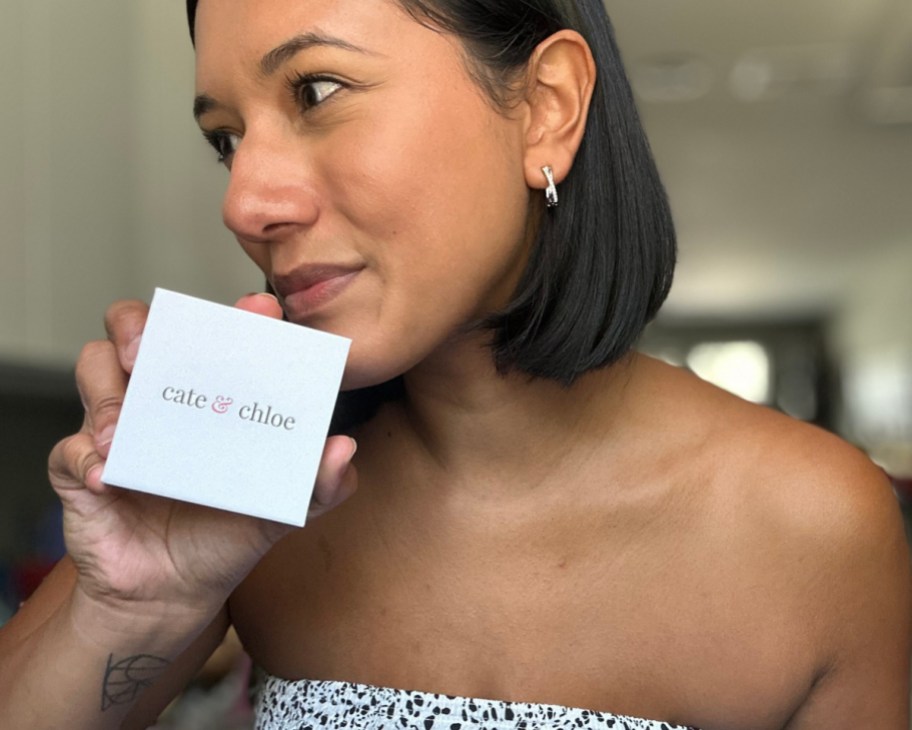 woman wearing hoop earrings holding box