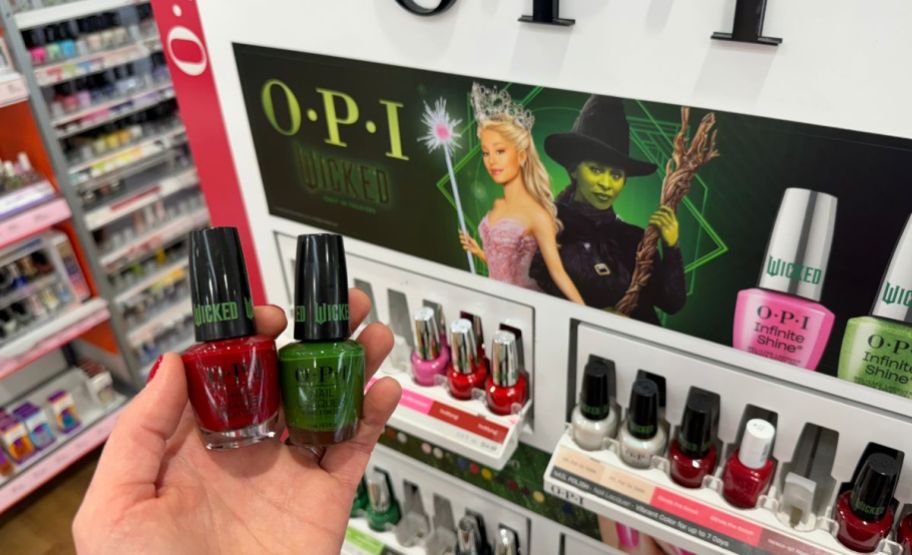 a womans hand holding two nail colors from the opi wicked collection