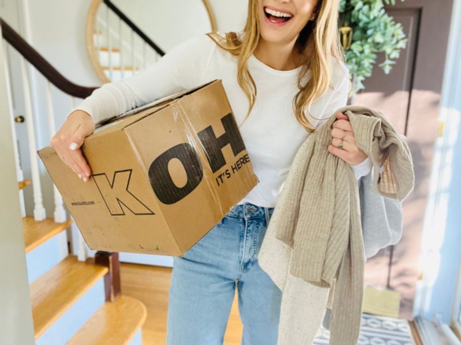 A Woman carrying a box and shirts from Kohl's