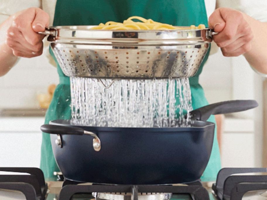 Woman lifting the metal steaming tray with pasta in it out of a Preferred Pan filled with boiling water.