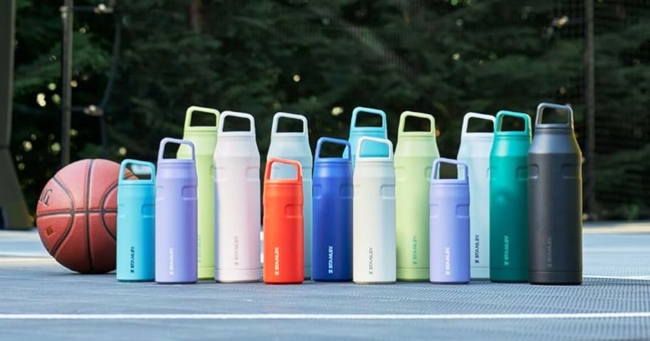 multiple stanley water bottles in various colors on basketball court