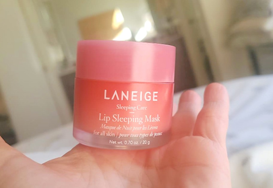 hand holding pink container of lip sleeping mask