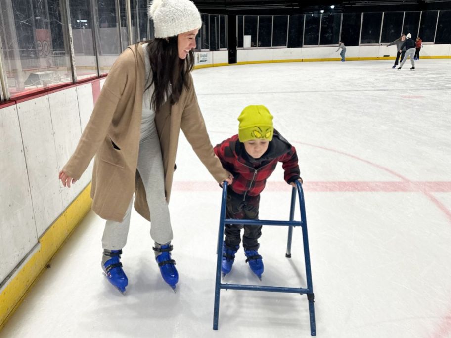 Woman helping a little boy ice skate at a rink