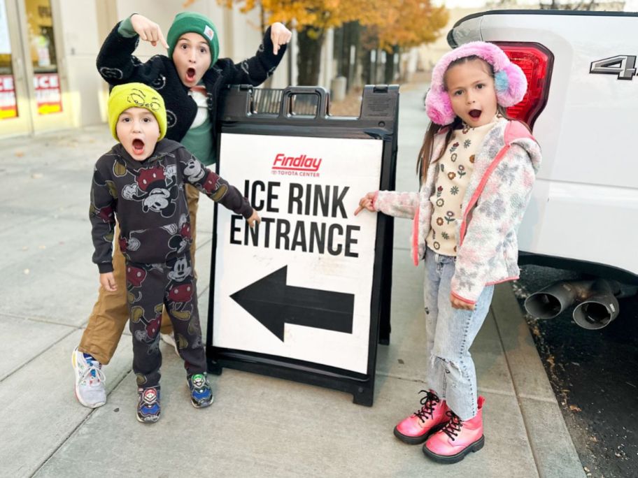 3 Kids very excitedly pointing at an Ice skating rink sign