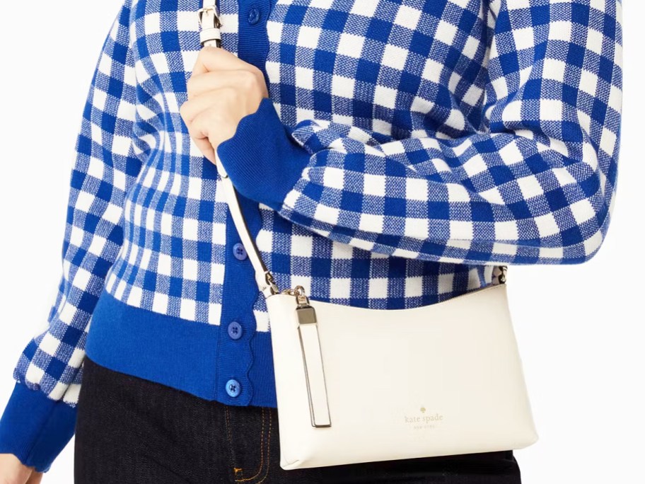 woman in a blue and white gingham sweater with white crossbody bag