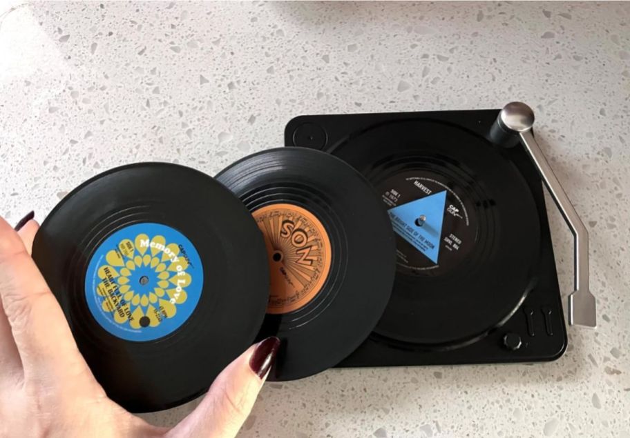 womans hand holding a record coaster