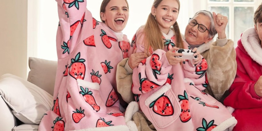 two girls wearing pink strawberry blankets 