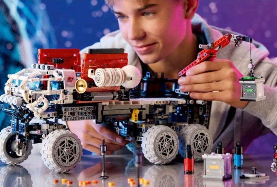 Teen boy constructing a LEGO Technic Mars Crew Exploration Rover Building Set