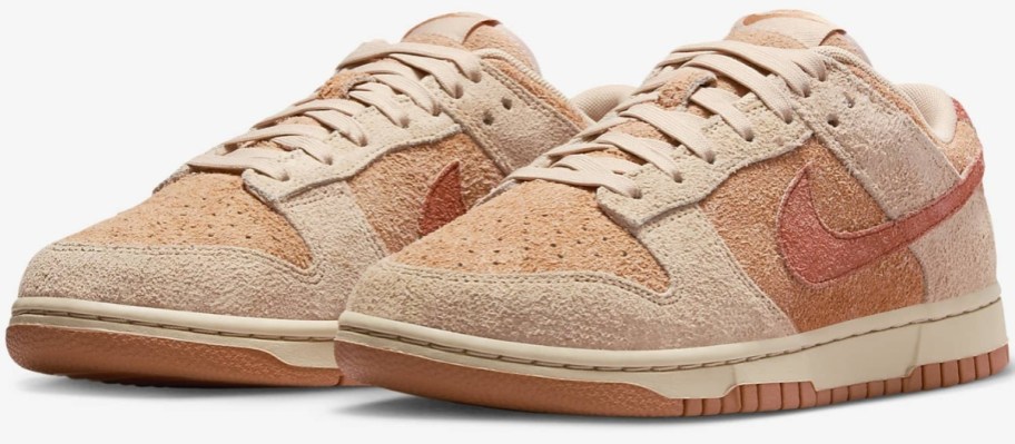 a pair of women's Nike Dunk style shoes in a pinkish peach color with a suede like texture