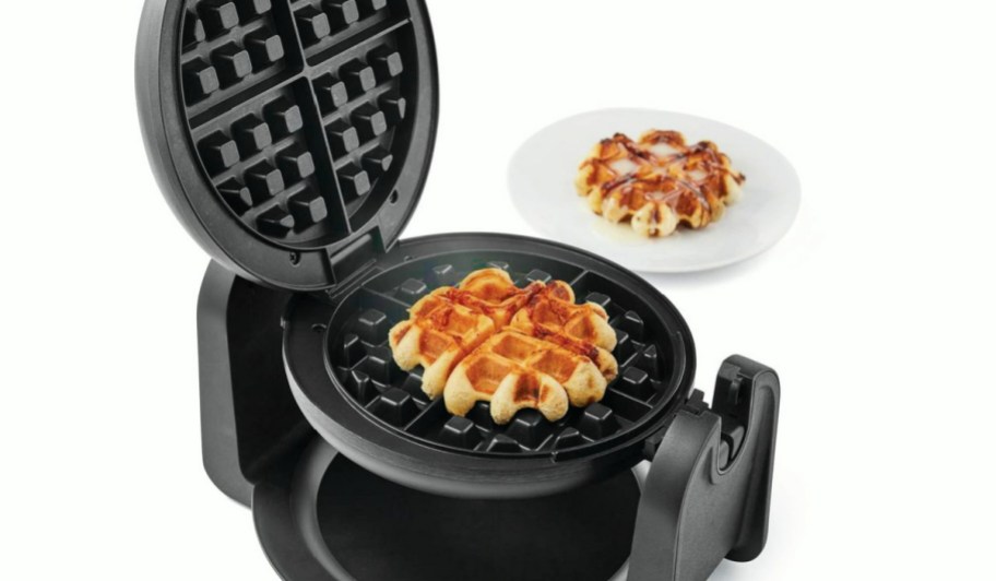 waffle in a Farberware Single-Flip Waffle Maker next to a white plate with a waffle on it